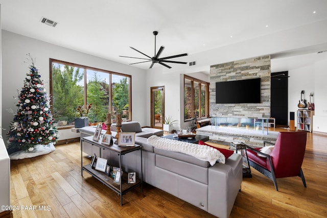 living room featuring a fireplace, light hardwood / wood-style floors, and ceiling fan