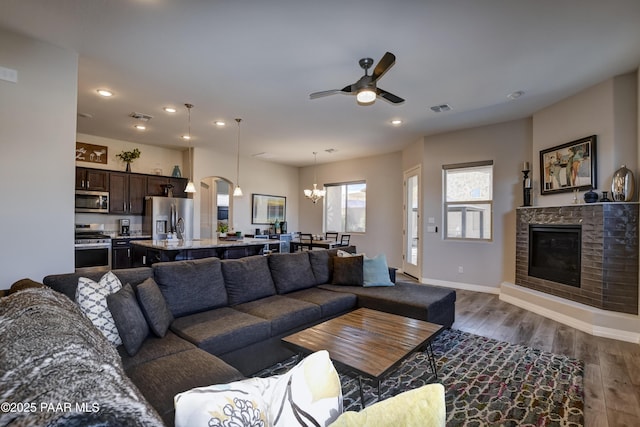 living room with dark wood-type flooring and ceiling fan with notable chandelier