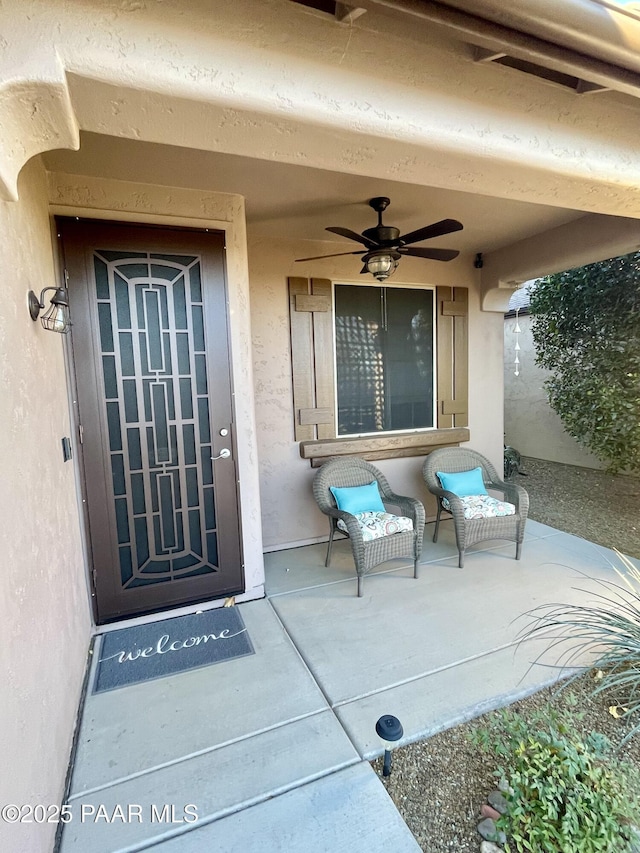 view of exterior entry featuring stucco siding and a ceiling fan