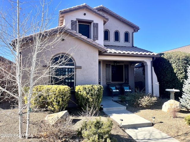 mediterranean / spanish-style house featuring a porch, a tiled roof, and stucco siding