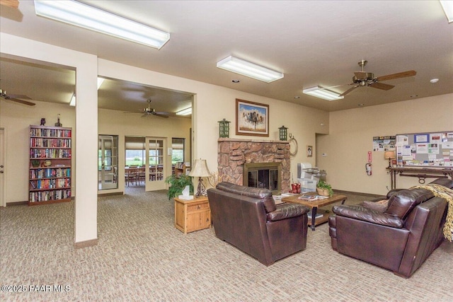living area with light carpet, ceiling fan, a stone fireplace, and baseboards