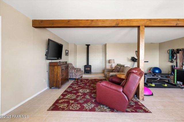 living room featuring a wood stove, tile patterned flooring, baseboards, and beamed ceiling