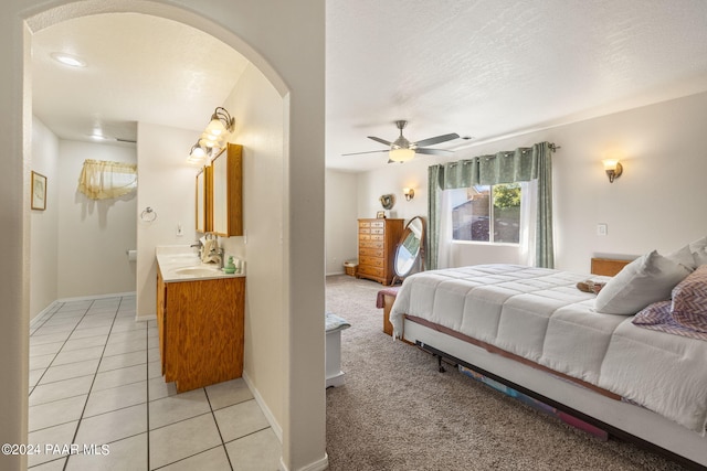 bedroom featuring ceiling fan, sink, light carpet, and a textured ceiling