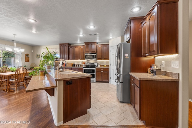 kitchen with pendant lighting, sink, light hardwood / wood-style flooring, stainless steel appliances, and a chandelier