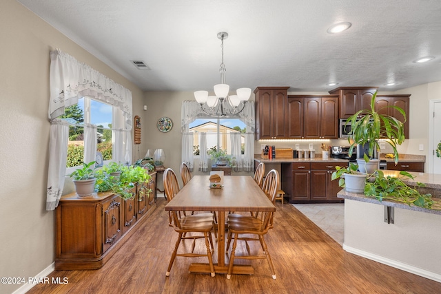 dining area with a notable chandelier, a textured ceiling, and light hardwood / wood-style flooring