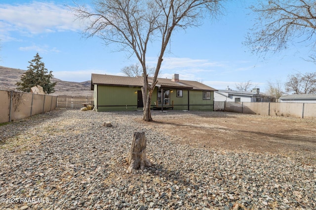 back of property with a fenced backyard and a chimney