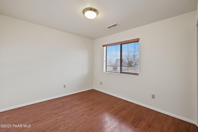 empty room featuring visible vents, baseboards, and wood finished floors