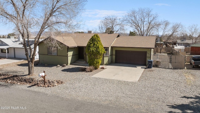 view of front of house with driveway, fence, an attached garage, a shingled roof, and a chimney