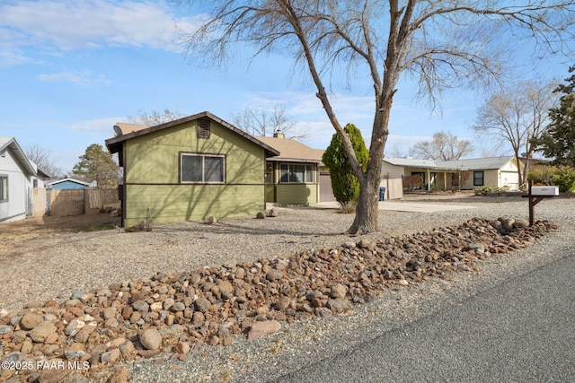 ranch-style house with gravel driveway, a chimney, and fence