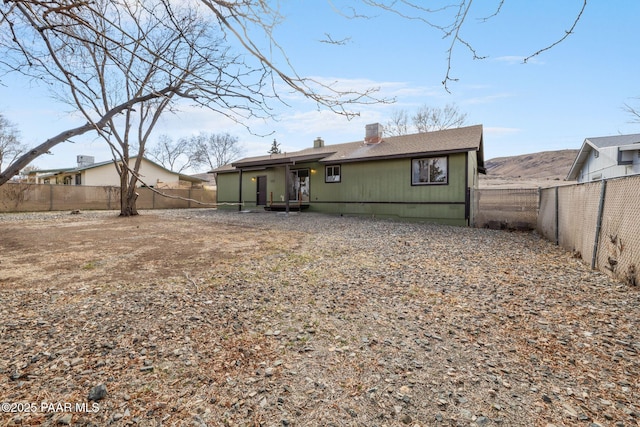 back of house featuring a fenced backyard and a chimney