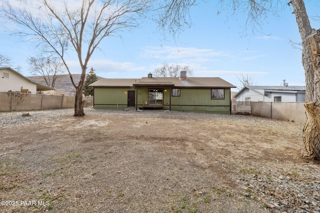 back of house featuring a fenced backyard and a chimney