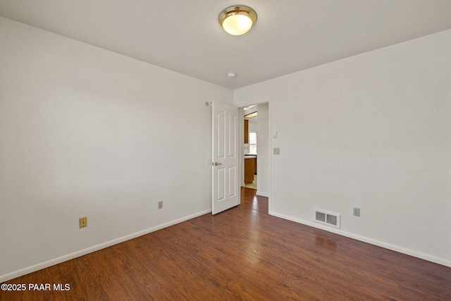 spare room with visible vents, baseboards, and wood finished floors