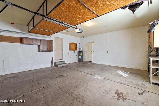 garage featuring a garage door opener, baseboards, and electric water heater