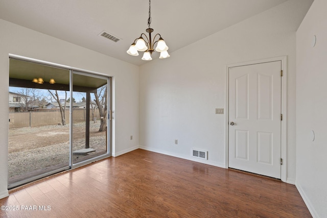 unfurnished room with an inviting chandelier, wood finished floors, visible vents, and baseboards