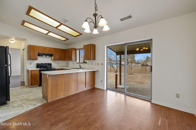 kitchen with visible vents, a notable chandelier, black appliances, a peninsula, and brown cabinetry