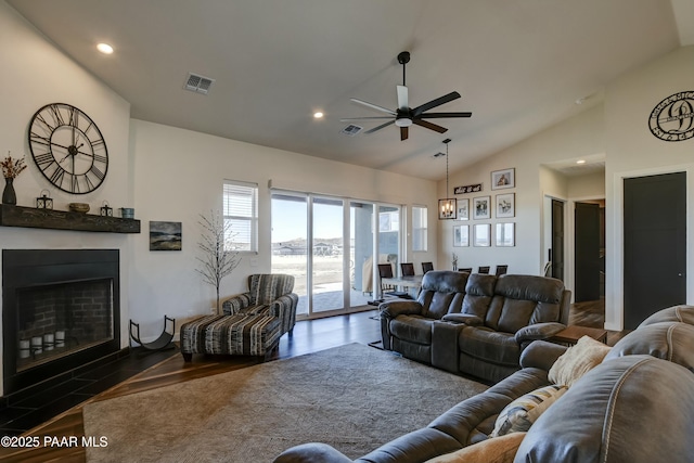 living area featuring a fireplace with flush hearth, ceiling fan, visible vents, and wood finished floors