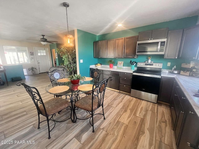 kitchen with stainless steel microwave, dark brown cabinetry, light wood-style flooring, light countertops, and range with electric stovetop