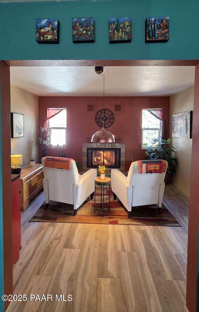 living room featuring visible vents, baseboards, light wood finished floors, and a fireplace