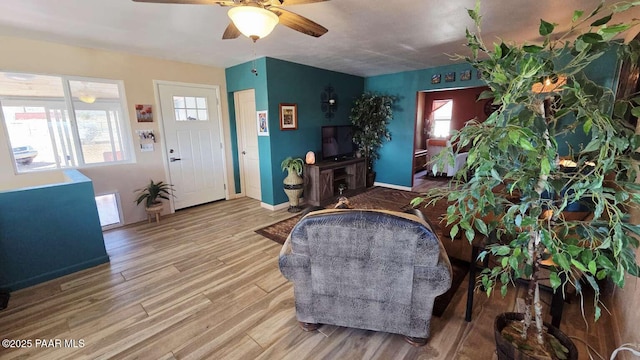 living room featuring ceiling fan, baseboards, and wood finished floors