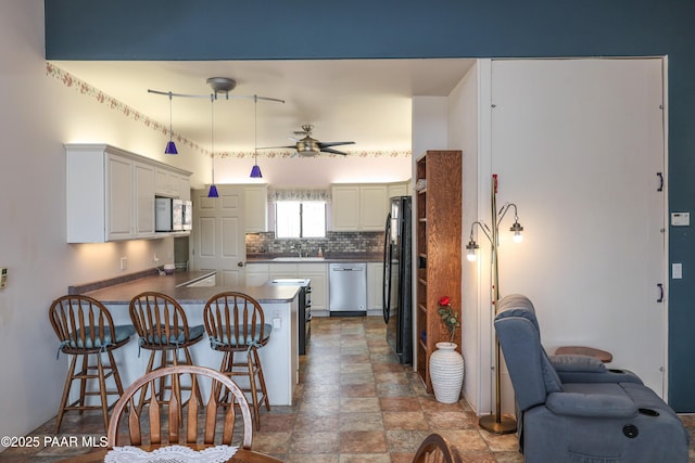 1980 S Koch Ranch Rd, Cornville, AZ 86325 - kitchen featuring a kitchen breakfast bar, a peninsula, backsplash, ceiling fan, and appliances with stainless steel finishes