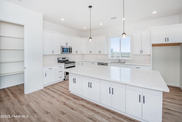 6881 E Bourbon Way, Prescott Valley, AZ 86315 - kitchen featuring appliances with stainless steel finishes, a center island, white cabinets, light wood-style flooring, and light countertops