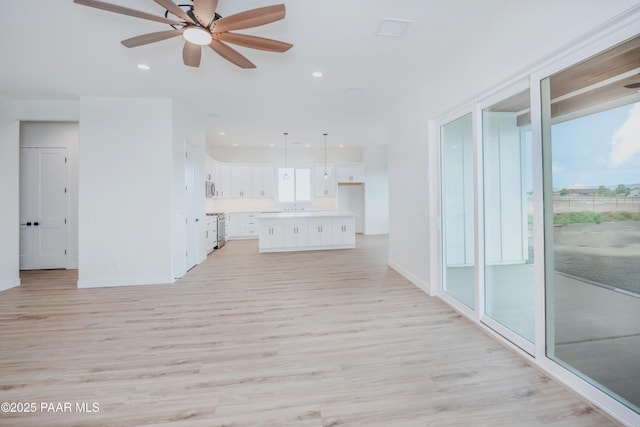 6881 E Bourbon Way, Prescott Valley, AZ 86315 - unfurnished living room featuring light wood-type flooring, a ceiling fan, healthy amount of natural light, and recessed lighting