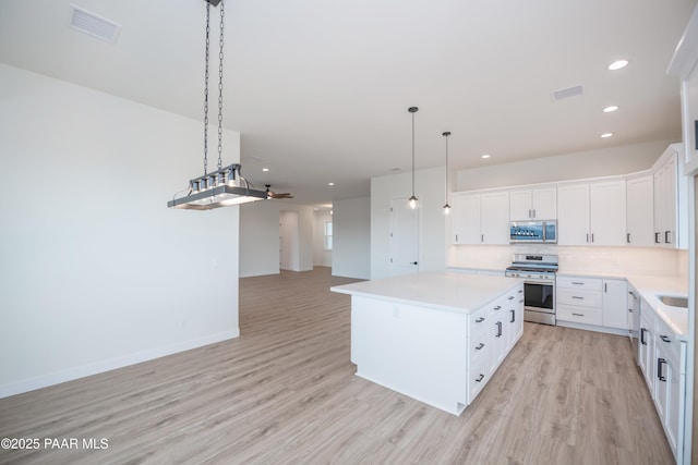 6881 E Bourbon Way, Prescott Valley, AZ 86315 - kitchen with stainless steel appliances, light wood-type flooring, a center island, backsplash, and light countertops