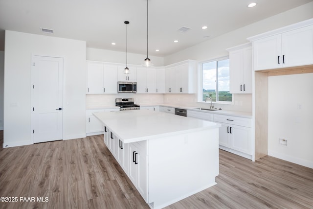 6881 E Bourbon Way, Prescott Valley, AZ 86315 - kitchen featuring appliances with stainless steel finishes, light wood-type flooring, a center island, white cabinetry, and recessed lighting