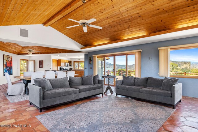 living area with beamed ceiling, a mountain view, a ceiling fan, and visible vents