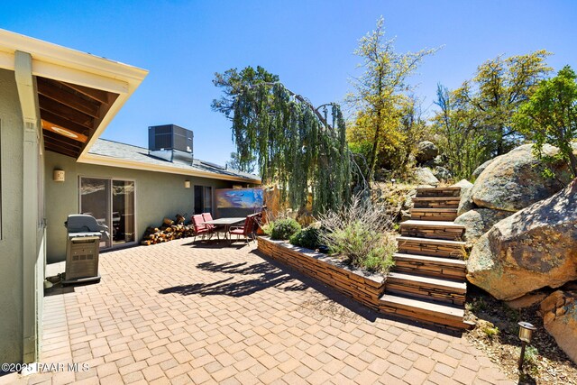 view of patio / terrace featuring outdoor dining area, a grill, and central air condition unit