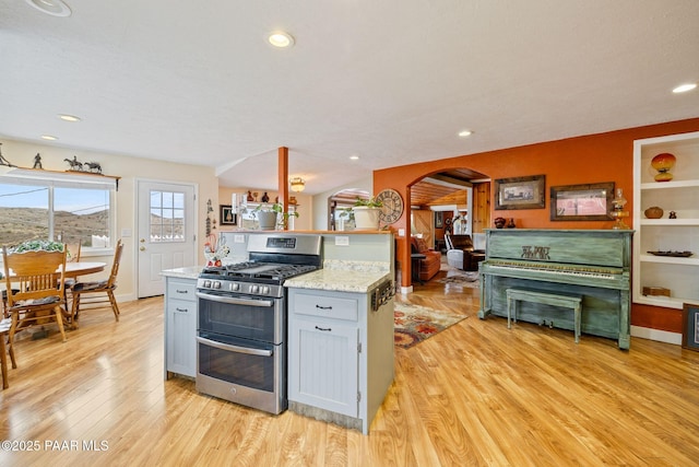 kitchen with gray cabinetry, double oven range, recessed lighting, arched walkways, and light wood-style floors