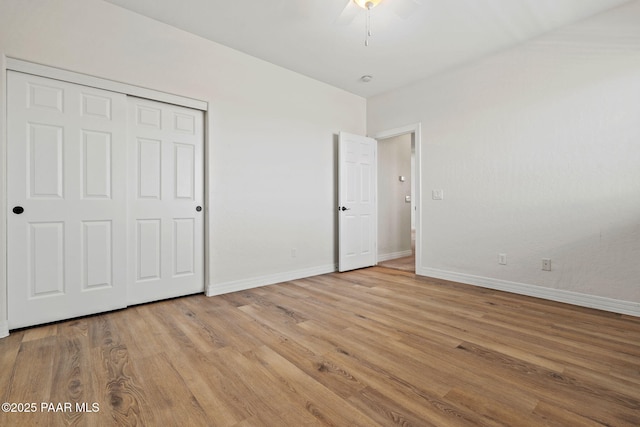 unfurnished bedroom with a closet, baseboards, and light wood finished floors