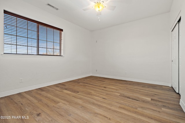 unfurnished bedroom featuring visible vents, baseboards, a closet, and wood finished floors