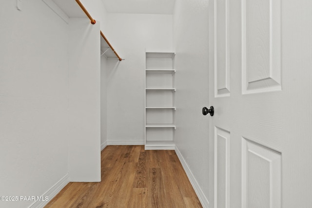walk in closet with wood finished floors