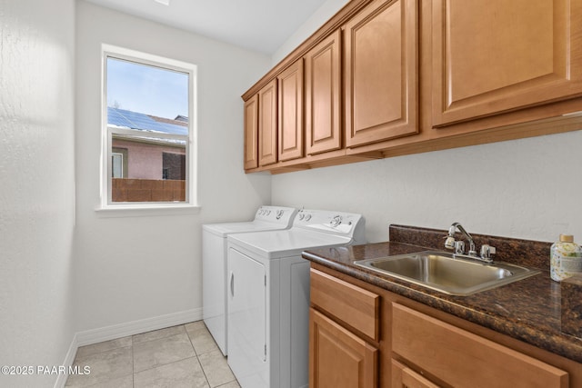 clothes washing area featuring separate washer and dryer, baseboards, light tile patterned flooring, cabinet space, and a sink