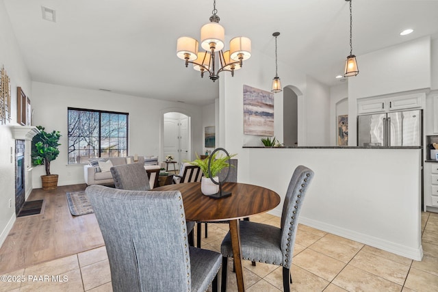 dining room featuring visible vents, baseboards, arched walkways, a chandelier, and light tile patterned flooring