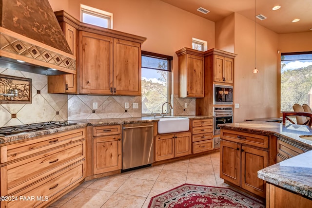 kitchen featuring premium range hood, sink, hanging light fixtures, light tile patterned flooring, and stainless steel appliances