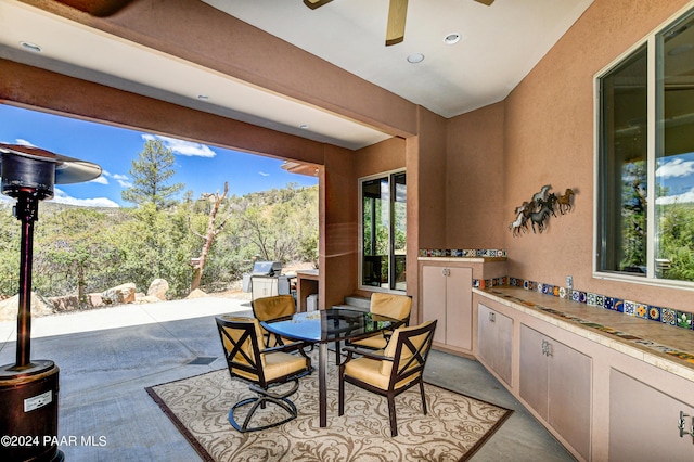 view of patio featuring ceiling fan, exterior kitchen, and grilling area