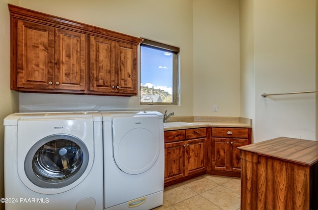 laundry room with cabinets, light tile patterned flooring, washer and dryer, and sink