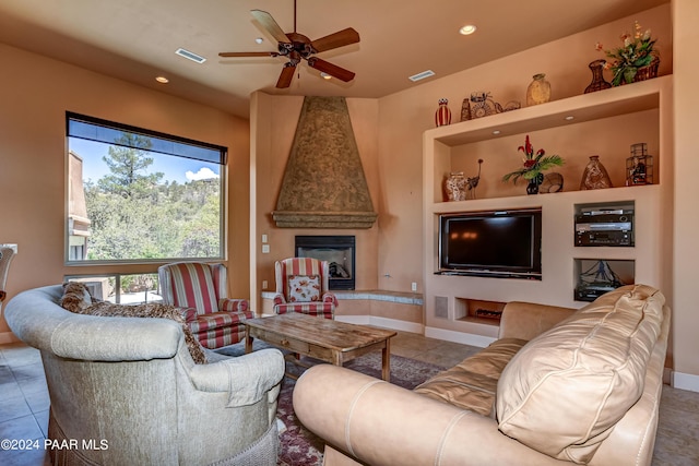 tiled living room with ceiling fan and a large fireplace