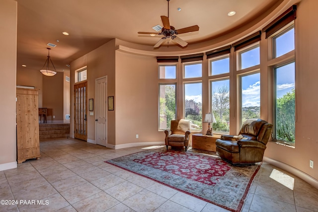 living area featuring ceiling fan, light tile patterned flooring, and a high ceiling