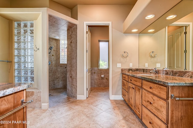 bathroom with tiled shower, vanity, and tile patterned floors