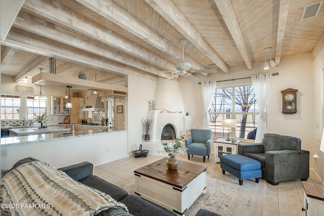 living area featuring tile patterned floors, visible vents, beam ceiling, and wood ceiling