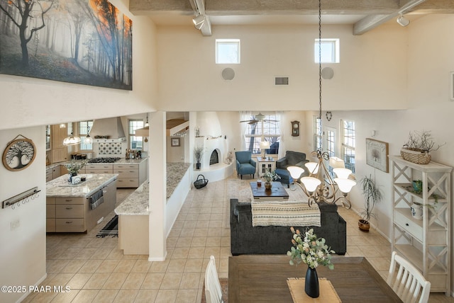 living area featuring light tile patterned floors, visible vents, a healthy amount of sunlight, and a fireplace with raised hearth