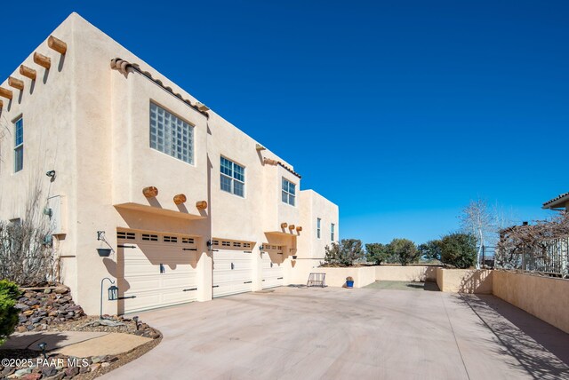 view of home's exterior with an attached garage, driveway, and stucco siding