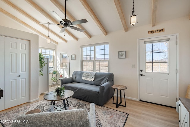 living area with vaulted ceiling with beams, a healthy amount of sunlight, light wood-style floors, and baseboards