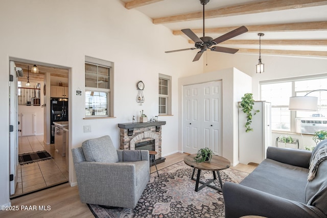 living room featuring beam ceiling, light wood-style flooring, plenty of natural light, and a fireplace