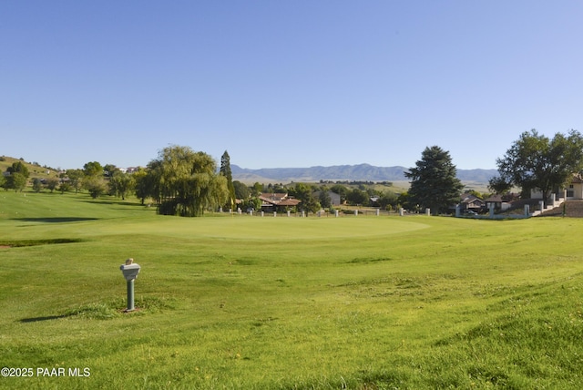 view of community featuring a lawn, a mountain view, and view of golf course