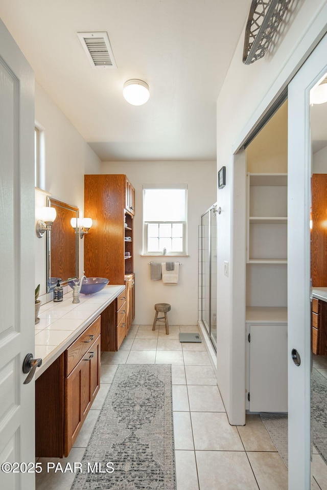 full bath featuring tile patterned flooring, visible vents, a stall shower, and vanity