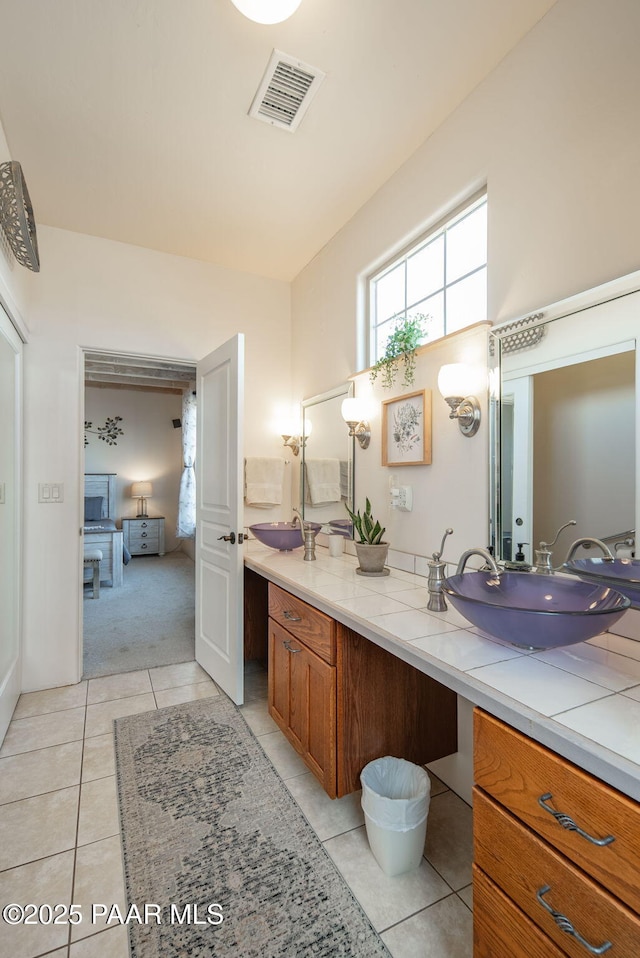 bathroom featuring a sink, visible vents, double vanity, and tile patterned flooring